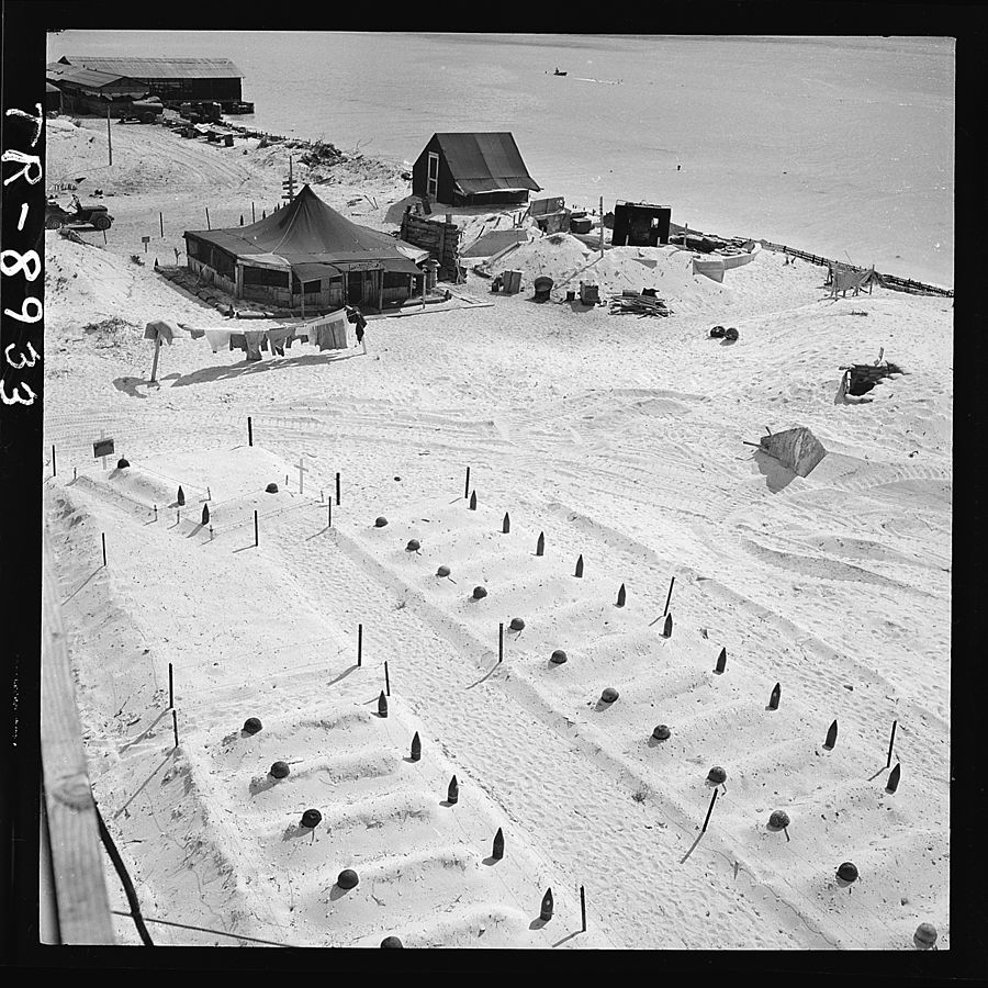 Graves of U.S. Marines who died taking Tarawa, before headstones were prepared. In the background are the first tents put up after occupation of the island. Image courtesy of Department of Defense.