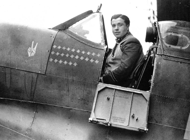 Lock in the cockpit of his Spitfire. Just below the cockpit are 26 Swastika emblems denoting aerial victories.
